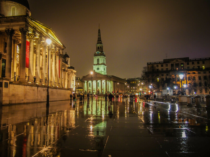 The National Gallery illuminated at night - and reflected in puddles in Trafalgar Square
