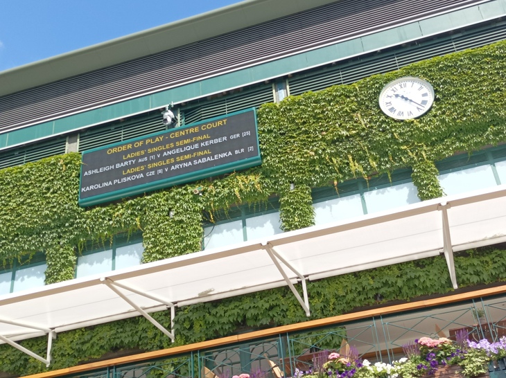 How to queue for Wimbledon:  The leafy frontage of Centre Court with a clock and order of play
