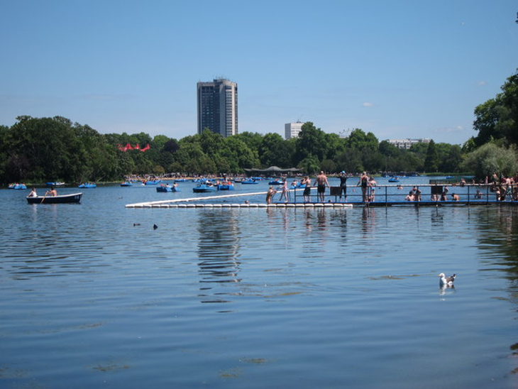 People lined up along the edge of, and swimming in, Serpentine Lido, a penned off area of the Serpentine in Hyde Park.