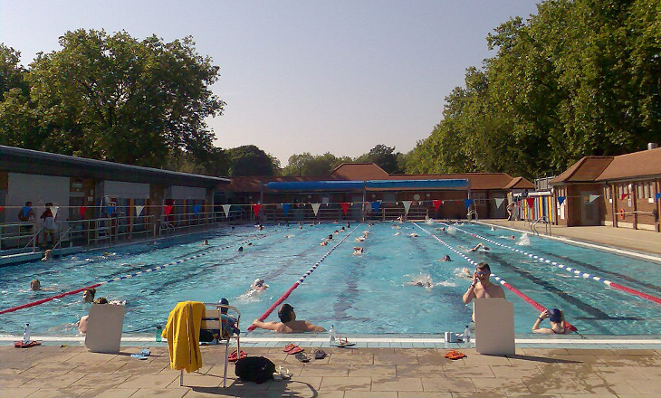 People swimming and playing in the outdoor pool at London Fields Lido