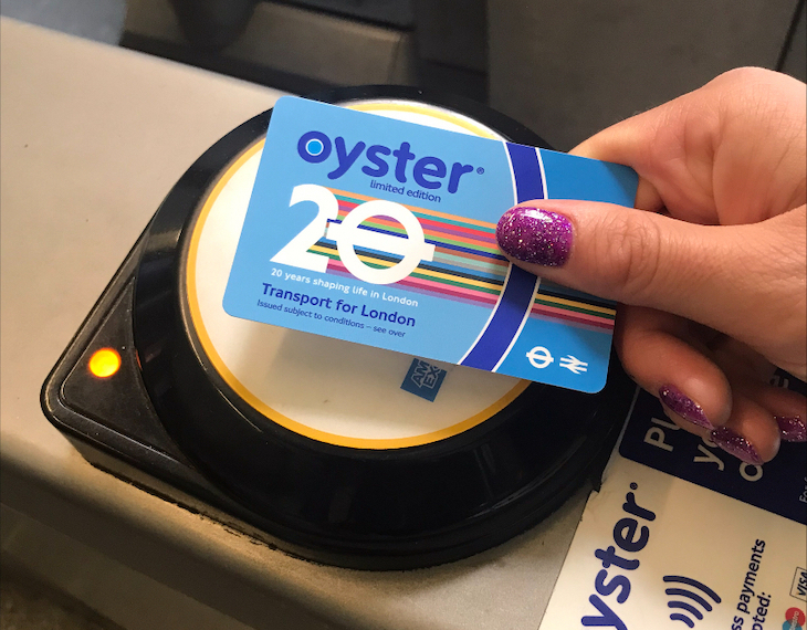 A hand swipes a special 20th anniversary oyster card over a reader