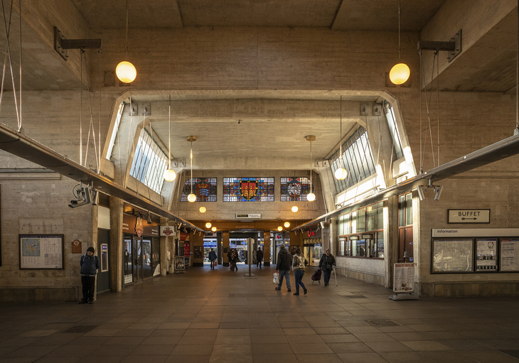 A vast concrete ticket hall with stained glass windows