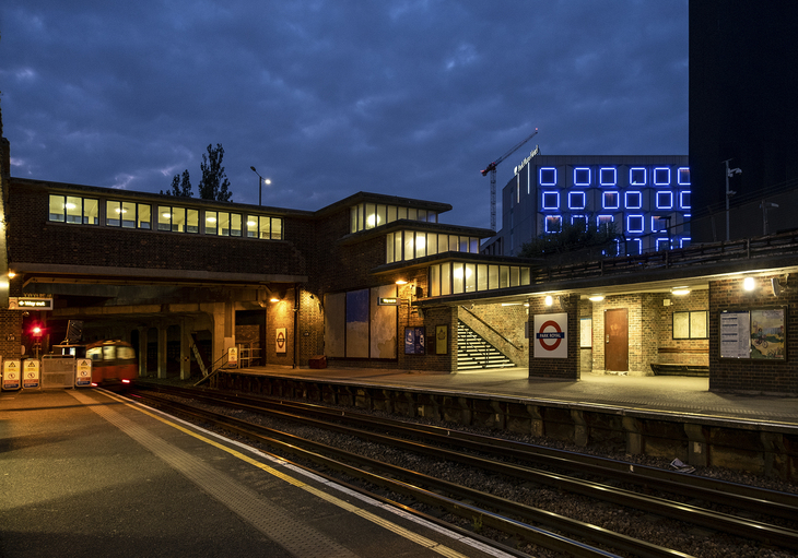An outdoor tube station lit at night - with various windows stepping down towards the platform