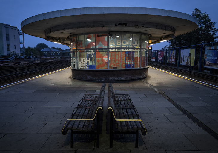 A curved waiting room/canopy over a tube station at night