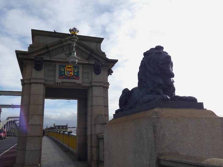 A gatehouse of Rochester Bridge, alongside a large sculpture of a lion lying down