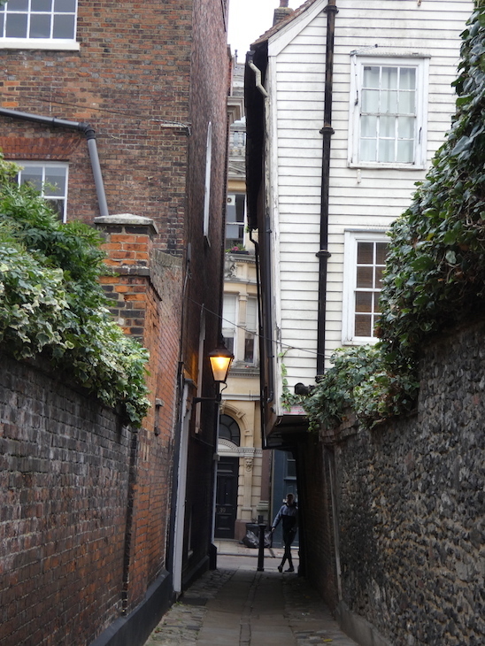 Two buildings leaning towards each other over a narrow pedestrian alleyway