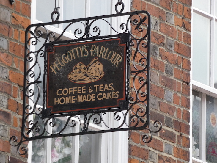 A wrought iron hanging sign outside a cafe 