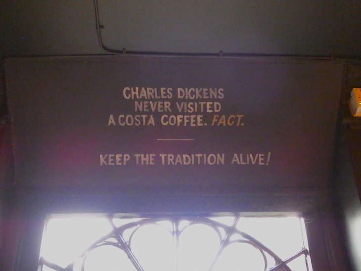 A handpainted sign above the cafe door saying "Charles Dickens never visited a Costa Coffee. Fact. Keep the tradition alive."