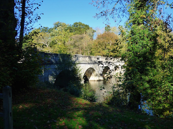 An arched stone bridge over Virginia Water lake