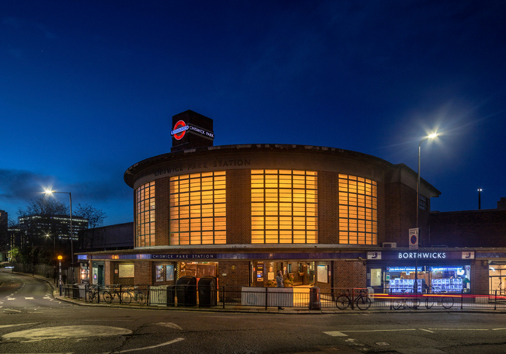 A curved station with huge windows glowing orange in the night sky