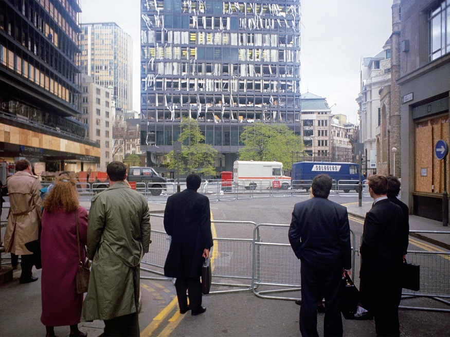 A small crowd looks at a blown up high rise