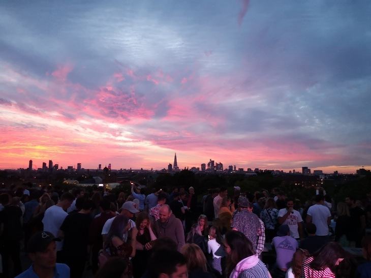 Best rooftop bars London: A crowded outdoor rooftop with purple/orange sunset