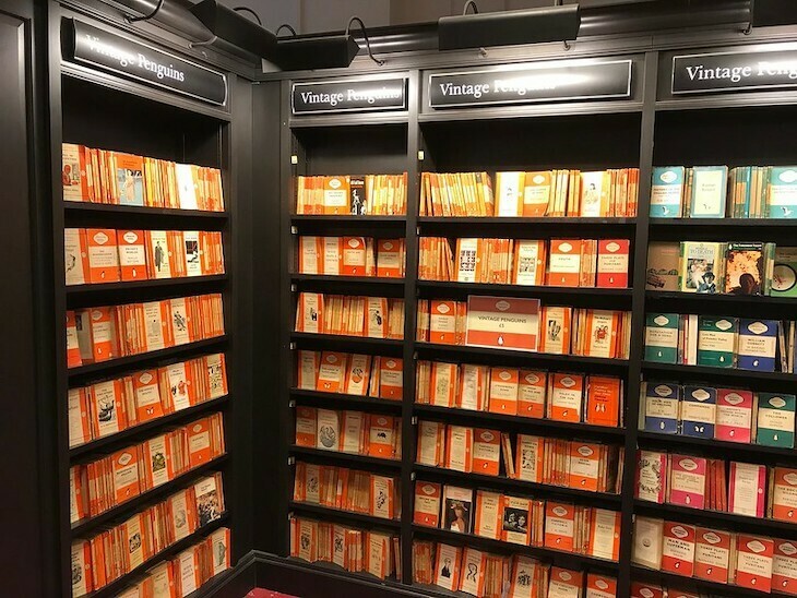 Penguin classics: a set of book shelves brimming with orange paperback Penguins