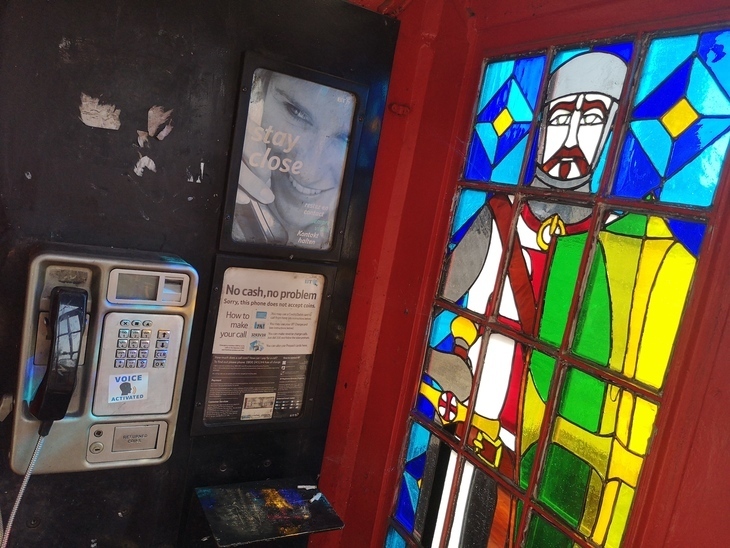 A stained glass window of a knight, in a phone box