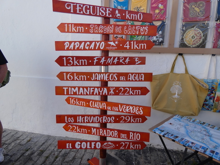 A decorative signpost mounted with arrows pointing in different directions to different sites on Lanzarote, including distances to them.