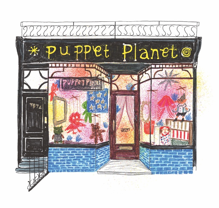 A black shopfront: Puppet Planet in yellow above the door - windows full of puppets
