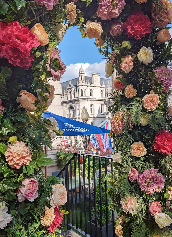 Best Rooftop Bars London: A flowery arch on a terrace, overlooking the top of a historic looking building