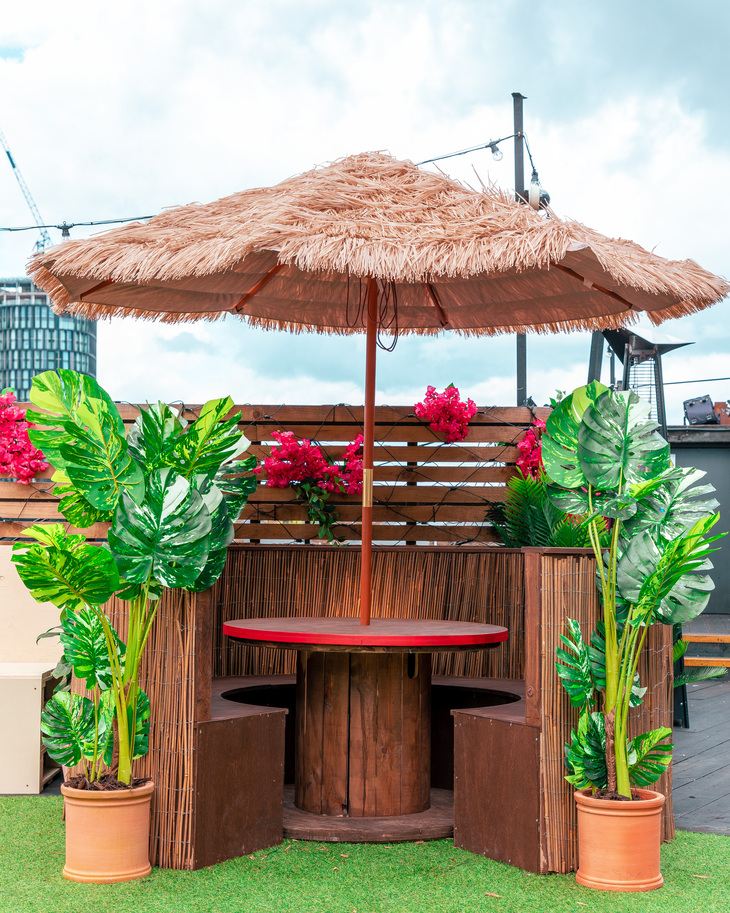 Best rooftop bars London: A tiki style parasol above a table flanked with palm leaves