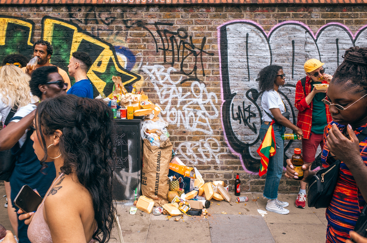 People eating a chilling in front of a wall covered in graffiti
