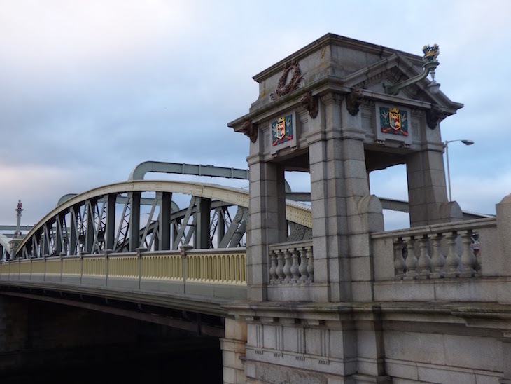 Rochester Bridge:huge metal spans with a square stone gatehouse structure at each end, with a coat of arms on each side of the gatehouse