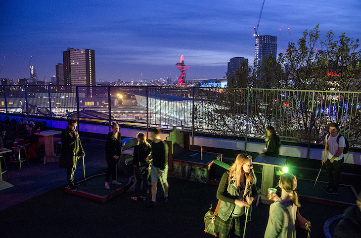 Best rooftop bars London: People drinking a playing crazy golf on a rooftop with east London - and the Orbit behind them