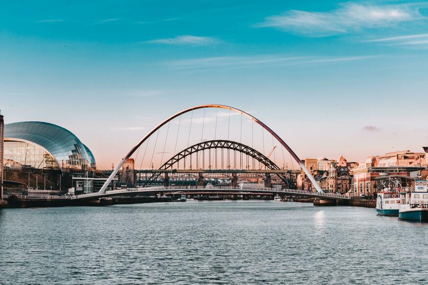 The river tyne runs through the centre of the image with the Gateshead centre on the left. Both the millenium bridge and the Tyne bridge are clearly visible over the Tyne. 