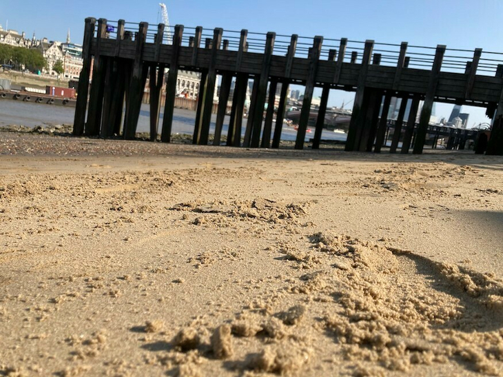 A sandy beach alongside the Thames, with a wooden pier jutting out into the water.