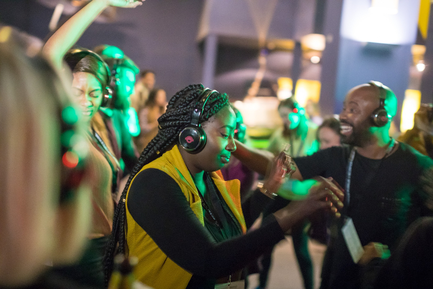 A woman wearing headphones dancing at a silent disco.