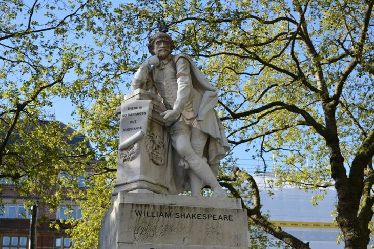 A statue of Shakespeare in front of some trees