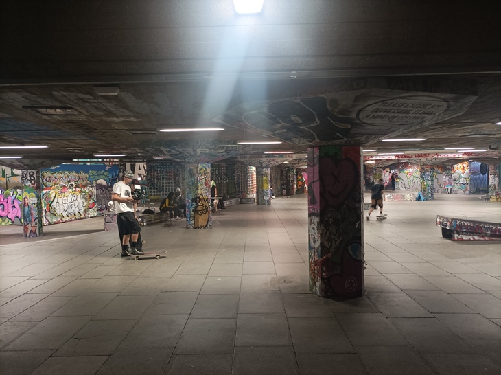 Skaters in a semi-subterranean graffitied skatepark
