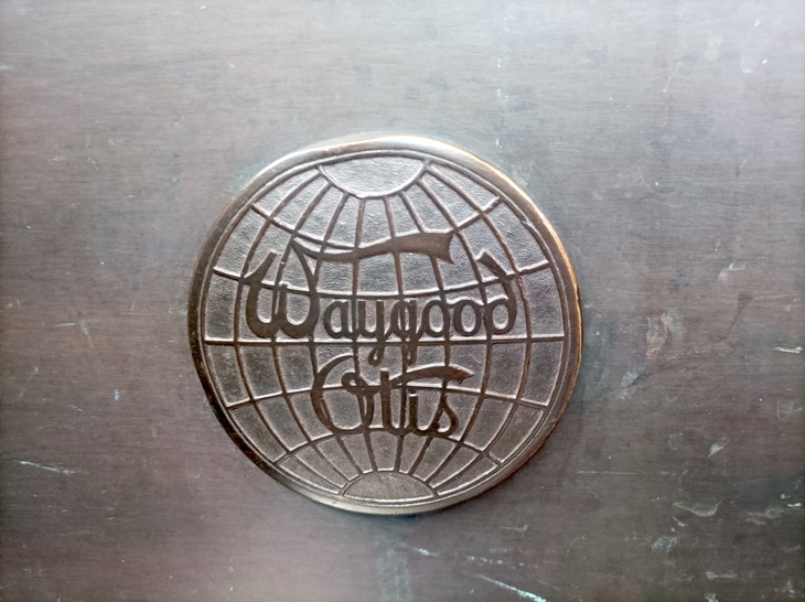 Closeup of a Waygood Otis logo in bronze on a escalator