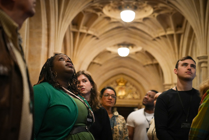 A tour group looking up at a gothic roof inside the Houses of Parliament