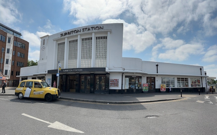 A panorama of Surbiton station with a yellow taxi to left