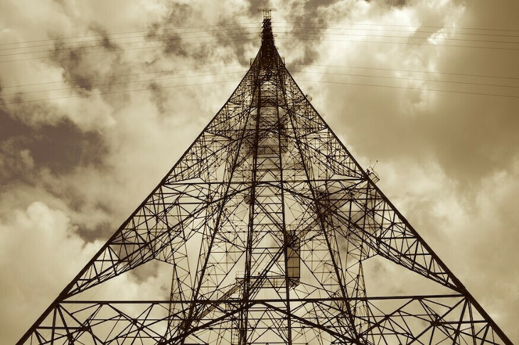 A soaring electricity pylon seen from below, in sepia