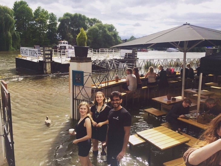 Best pub gardens London: people standing in a flooded beer garden