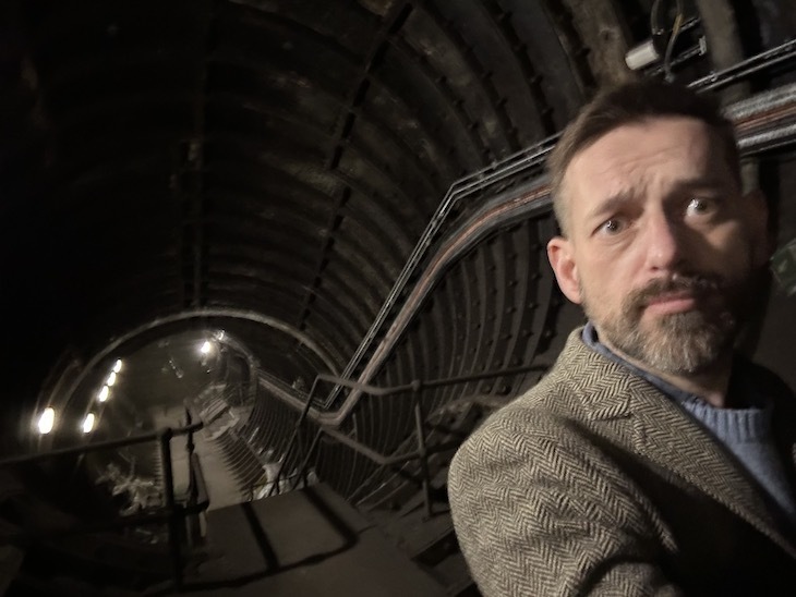 A bearded man looking slightly scared in a tube tunnel
