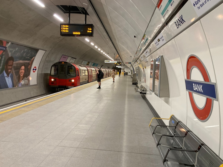 A tube train pulling into an almost empty platform at Bank station.