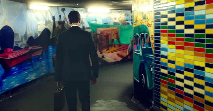 A man walking through the underpass, its walls lined with colourful tiles