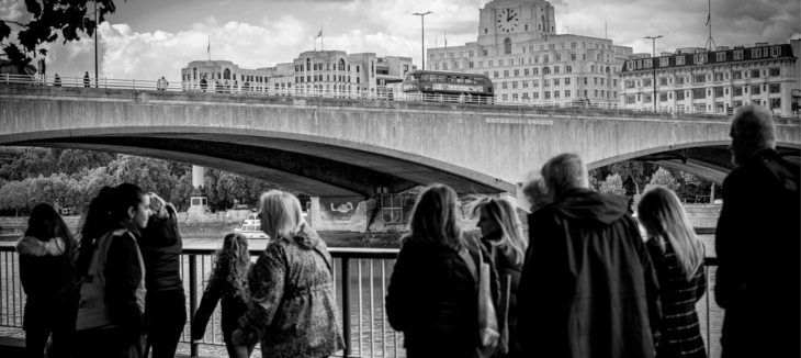 People along the embankment in the foreground, with Waterloo Bridge in focus in the background