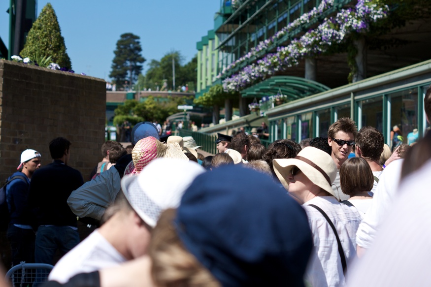 How to queue for Wimbledon: A crowd of people in front of the purple floral baskets of Wimbledon