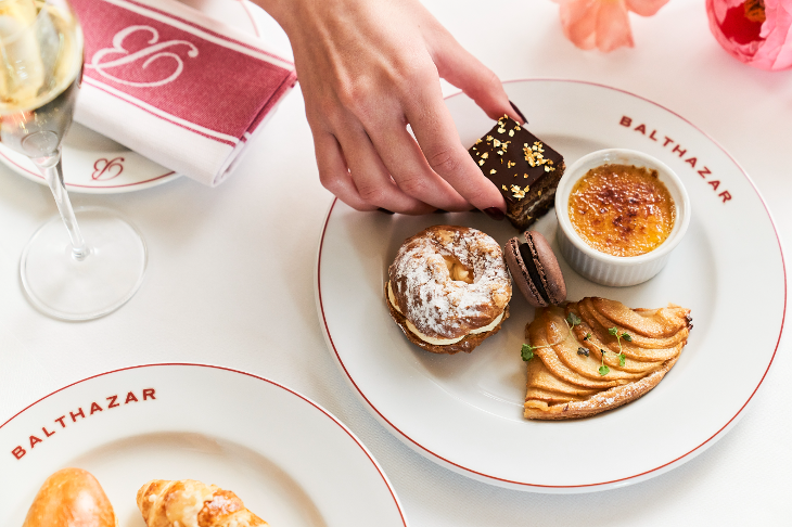 A hand reaching out to a plate filled with desserts.