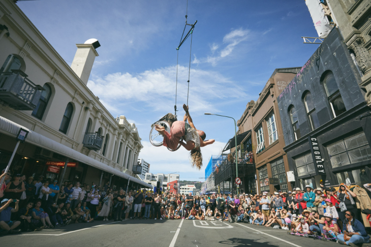 Autumn in London: two performers, one in a wheelchair, performing in the air above crowds in a street.