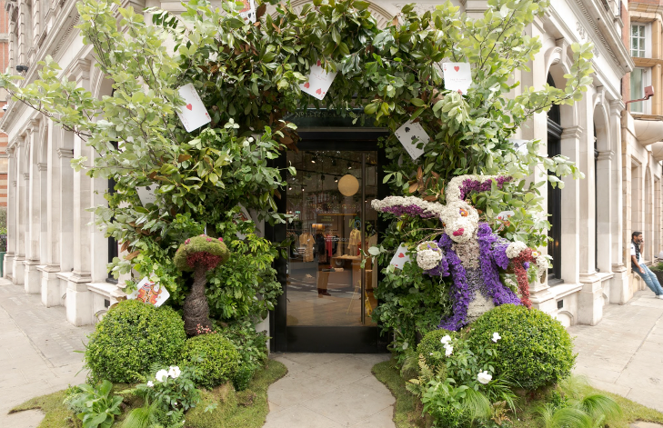 Chelsea in Bloom: a shop doorway with an arch of greenery on an Alice in Wonderland theme, featuring playing cards, and a white rabbit made from flowers