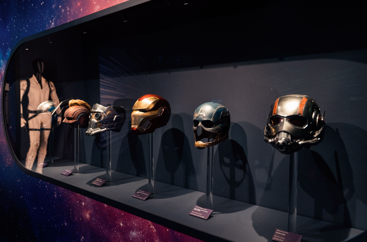A collection of helmets from Marvel films in a display cabinet