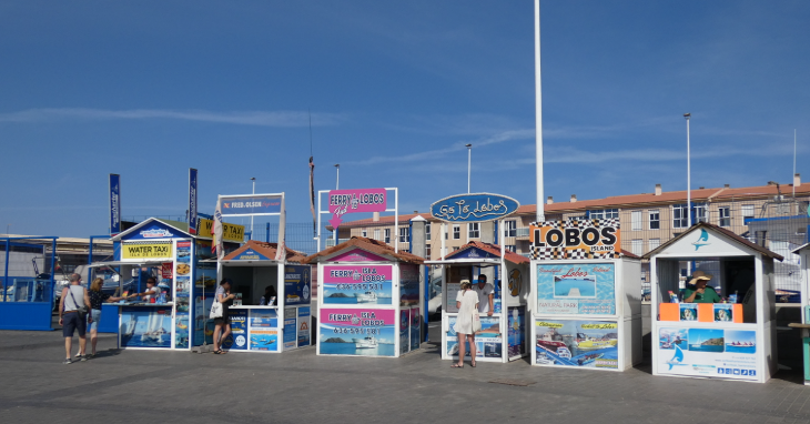 Corralejo in Fuerteventura: huts with representatives of different tour companies selling trips to Los Lobos, located in Corralejo Harbour