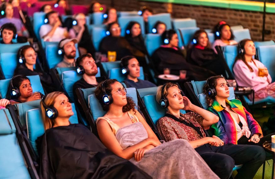 Horror film screenings: an audience sitting down wearing headphones and  watching a screen.