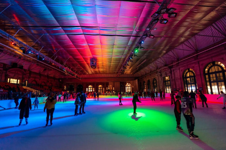 The ice rink at Alexandra Palace, dimly lit with multi-coloured spotlights