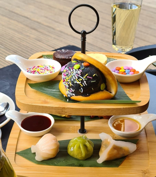 International afternoon tea: various sweet and savoury dim sum served on a two-tier wooden stand