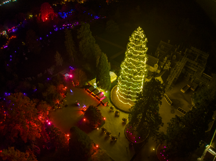 A very tall Christmas tree with Christmas lights wrapped around it, photographed from above.