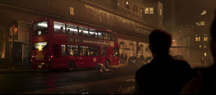 A silhouetted figure looks on at a number 25 bus at night